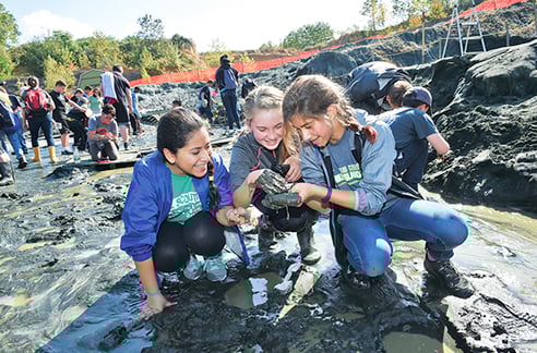 Three students digging in the mud.