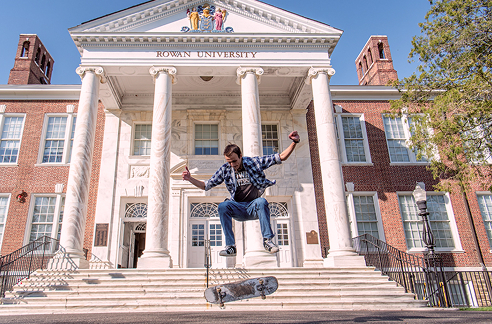 A student does a jump on a skateboard.
